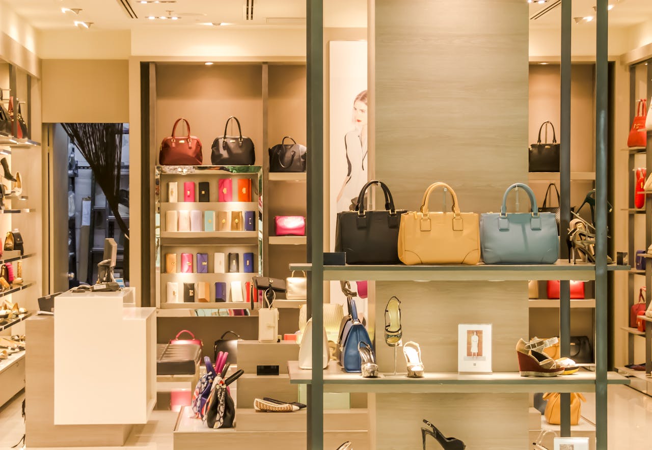 about-us Chic boutique with a variety of handbags and shoes elegantly displayed on shelves.