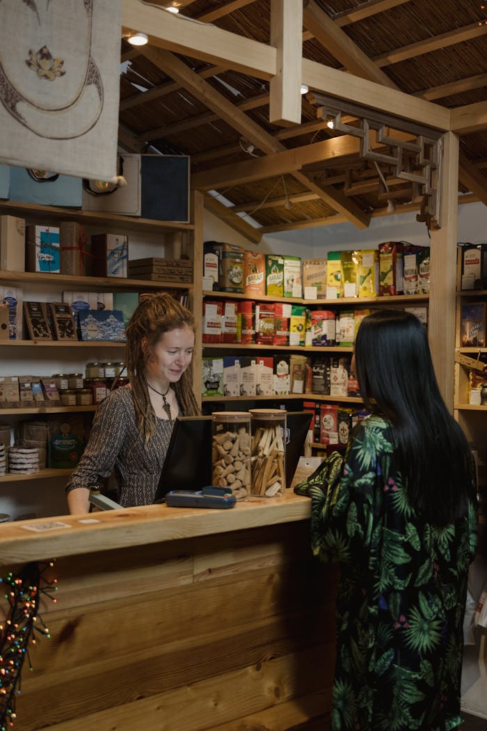 who-we-are Woman customer interacting at a wood-accented store checkout, surrounded by various merchandise.